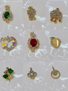 Assorted gold clover and heart pendants with colorful gemstones on a reflective surface