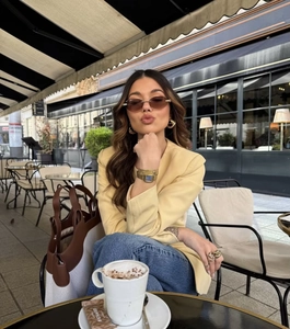 Detail of yellow round neck single-breasted blazer styled with jeans in an outdoor cafe
