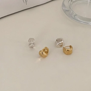 Detailed view of minimalist oval stud earrings in polished gold and silver finishes