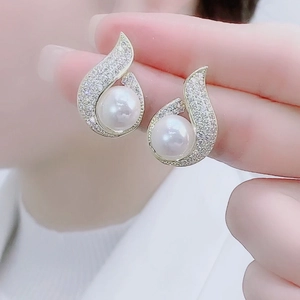 Macro detail of French style teardrop pearl earrings with shimmering pavé zircon accents