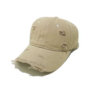 Macro view of distressed khaki baseball cap with ripped details and white contrast stitching