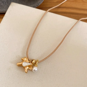 Détail du pendentif pégase doré avec ailes émaillées et une perle sur cordon tressé