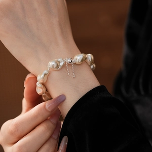 Detail of baroque pearl bracelet with silver magnetic clasp and safety chain on wrist