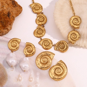 Detail of 18K gold plated shell necklace and baroque pearl earrings on a marine backdrop