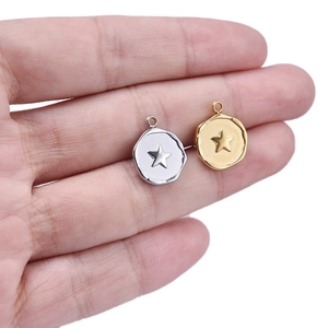 Close-up of irregular round gold and silver star pendants resting on a palm
