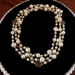Detail of multi-layer camellia baroque pearl necklace with black enamel pendant detail