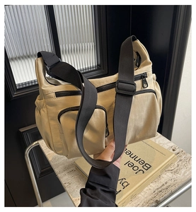 Detail of beige nylon crossbody bag with black contrast zippers and adjustable strap