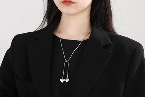 Detailed view of silver Y-shaped lariat necklace with two 3D heart pendants on a model