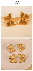 Detailed view of 18K gold butterfly earrings with intricate striped wings on ceramic display