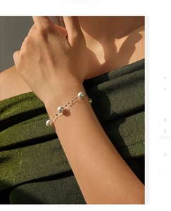 Detail of s925 silver pearl bracelet on model wrist with GOOD LUCK engraving