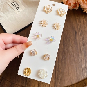 Close-up of five pairs of floral stud earrings with pearls and gold-tone finish