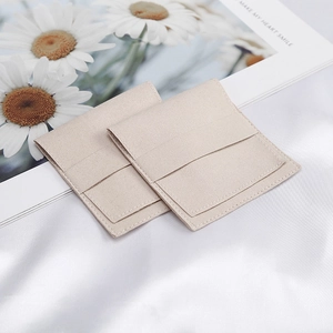 Detail of square beige microfiber jewelry envelope pouch on silk background fabric