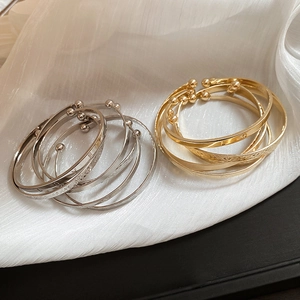 Detail of gold and silver multi-layer open bracelets with LOVE engraving on silk