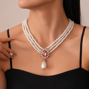 Detail of baroque multi-layer pearl necklace with pink gemstone and drop pearl pendant