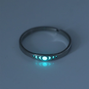 Macro view of luminous moon phase patterns glowing in cyan on a silver stainless steel ring