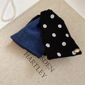 Detail of polka dot fabric scrunchie with a gold love engraved oval metal charm