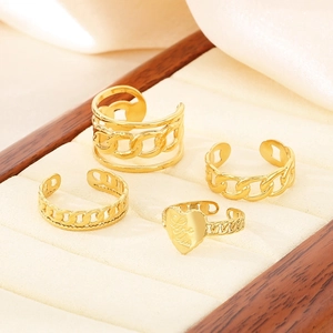 Set of four gold hollow twisted rings with heart and chain details on a jewelry tray
