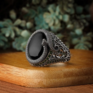 Detailed view of men's vintage copper ring with black oval stone and green side crystals