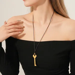 Collier pendentif clé dorée minimaliste avec cordon noir sur un mannequin de mode