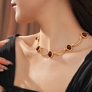 Detail of vintage gold necklace featuring deep red oval gemstones and woven chain links
