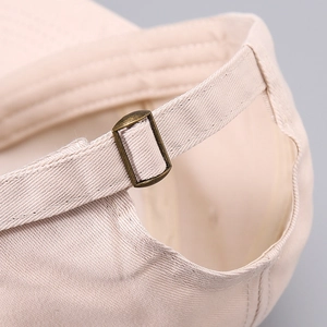 Detail of beige twill cotton baseball cap featuring adjustable bronze metal buckle