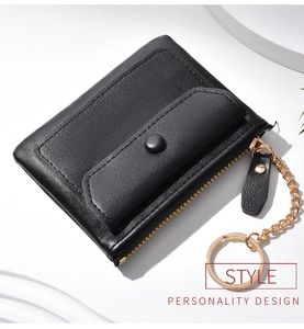 Close-up of black leather coin purse with golden zipper and keychain chain detail