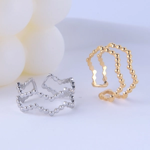 Close-up of wavy beaded open rings in gold and silver finish on a clean background