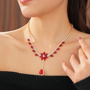 Close-up of luxury necklace with red teardrop zircon stones and golden floral motifs