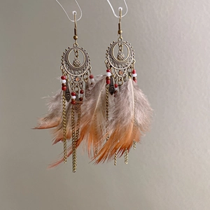 Macro detail of bohemian feather earrings with bronze hollow rings and beaded chains