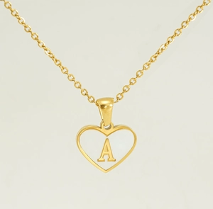 Detail of a golden heart pendant featuring an inlaid letter A and hollow frame design