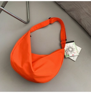 Detailed top view of an orange half-moon nylon crossbody bag with an adjustable strap