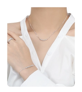 Gros plan d'un collier et d'un bracelet minimalistes en argent S925 à perles sur mannequin