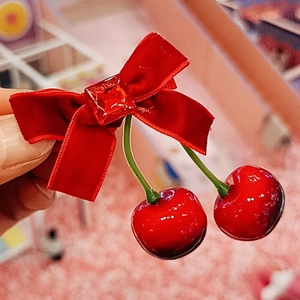 Détail de la pince à cheveux noeud en velours rouge avec cerises et pierre précieuse rouge