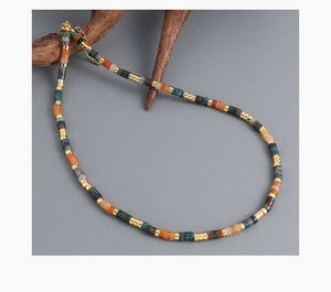 Close-up of bohemian beaded necklace with colorful cylindrical beads and golden clasp