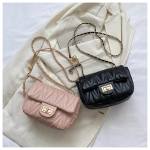 Detail of pink and black quilted leather bags with gold chain straps on white suit
