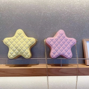 Detailed view of yellow and pink star-shaped quilted chain bags on a wooden shelf