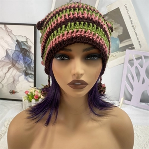 Detail of striped knitted cat ear beanie with pom-pom tassels and chunky crochet texture