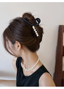 Pince à cheveux noire mate avec perles portée par un mannequin dans un cadre naturel