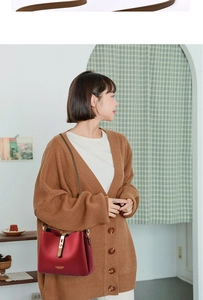 Detail of red crossbody bag with KESSGIH GADTN lettering worn by model in brown cardigan