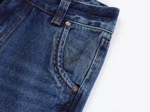 Detailed close-up of dark blue denim pocket with orange stitching and copper rivets