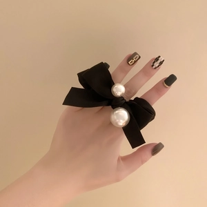 Elegant black velvet bow hair scrunchie with white pearls shown on a model wrist
