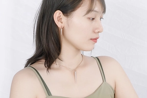 Detail of rose gold conical screw pendant necklace and earrings worn by model