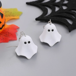 Macro shot of white ghost earrings with silver hooks on a Halloween-themed background