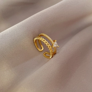 Minimalist double-layered gold ring with a triangle zircon stone on a silk background