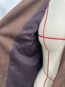 Detail of brown faux suede jacket featuring smooth deep purple satin inner lining