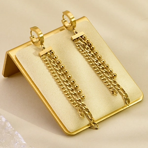 Detailed view of gold multi-layer chain tassel earrings on a sleek metal display stand