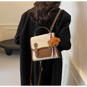 Detail of fashion crossbody bag with plush dog charm and stylish ribbon accessory