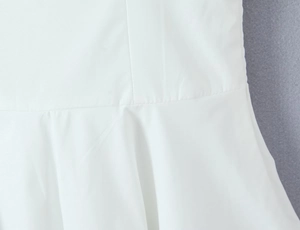 Detailed close-up of the fine stitching and white woven fabric texture of the dress