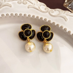 Macro view of vintage floral earrings with black clover petals and pearl drop detail