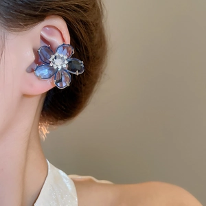 Close-up of blue zircon flower ear cuff with sparkling crystal core on model's ear